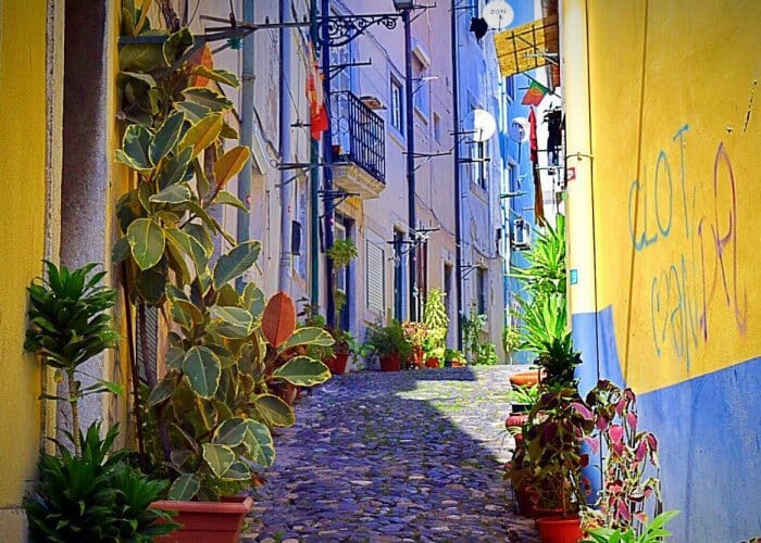 Lisbonne plus calme hors saison : ruelle pavée bordée de plantes et de façades colorées