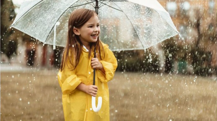 Que faire à Lisbonne sous la pluie : enfant en imperméable jaune sous un parapluie transparent